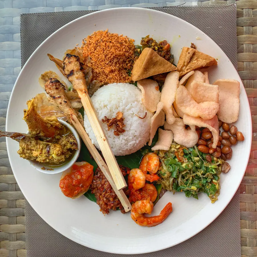 A plate of nasi campur with rice, satay and sambal