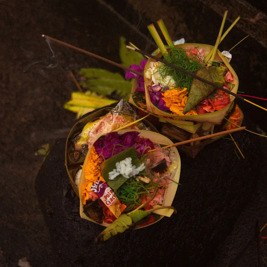 A canang sari offering with flowers on a stone floor