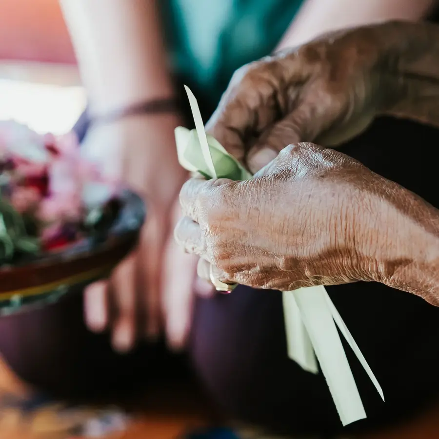 Hands folding palm leaves into an offering