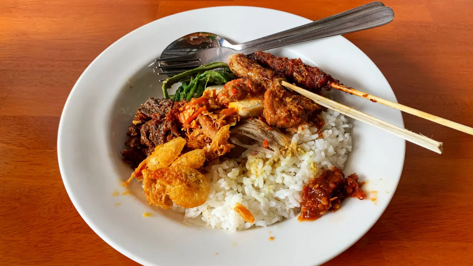 A plate of nasi campur with rice, meat and vegetables