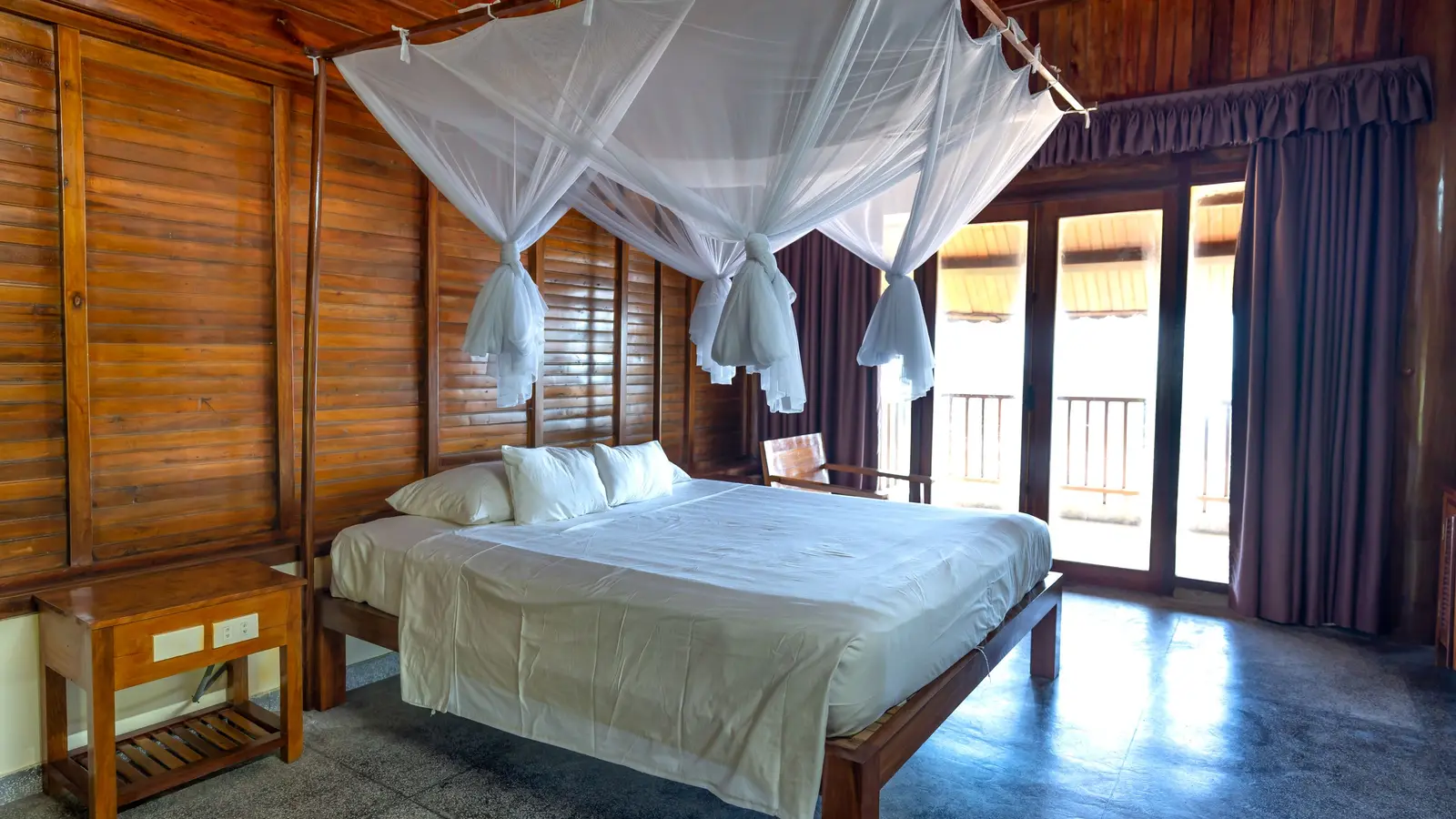 A wooden bedroom with a canopy bed and mosquito net