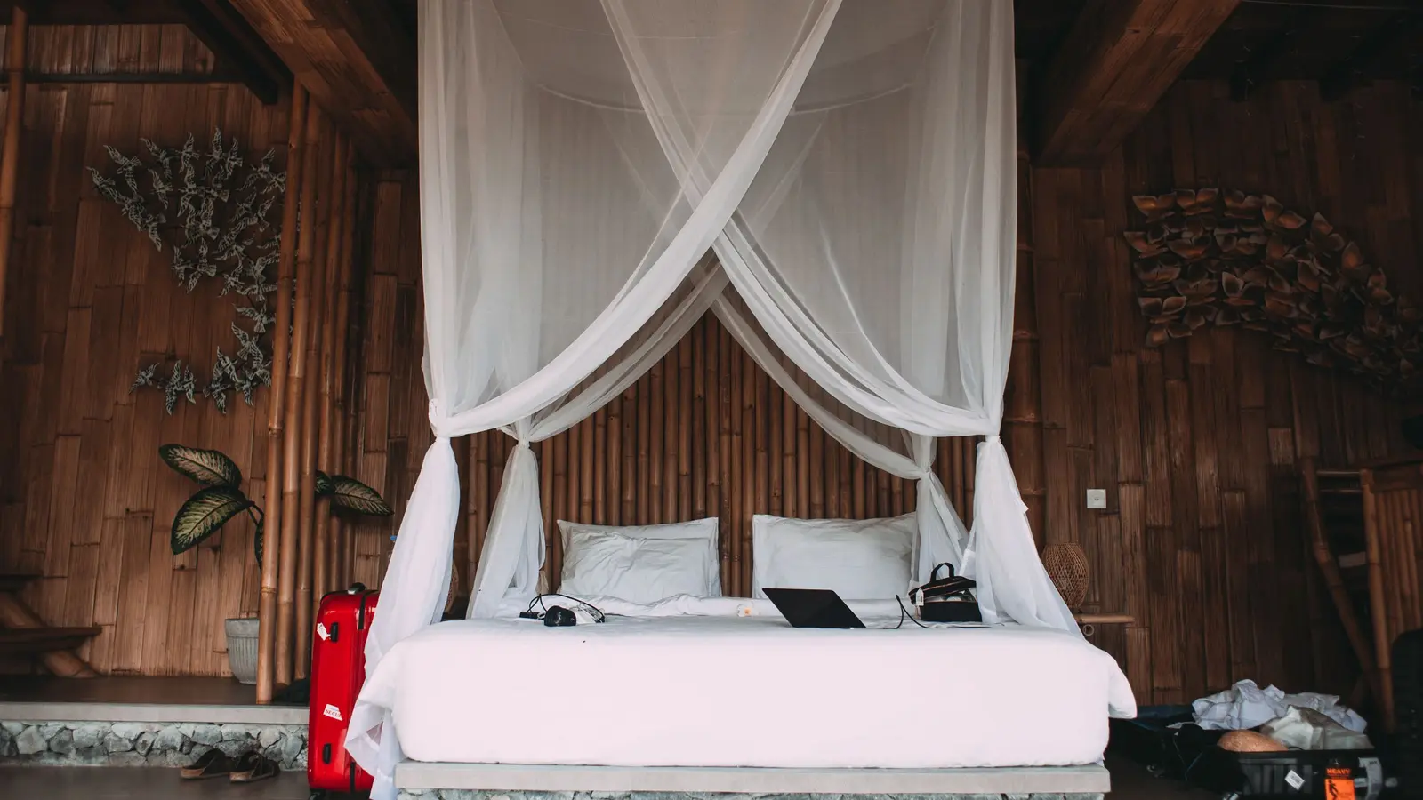 A bed with white linen and woven bamboo walls